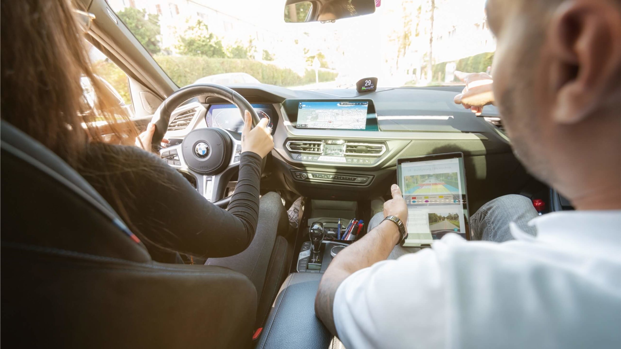 Fahrschülerin und Fahrlehrer im Auto während einer Fahrstunde.