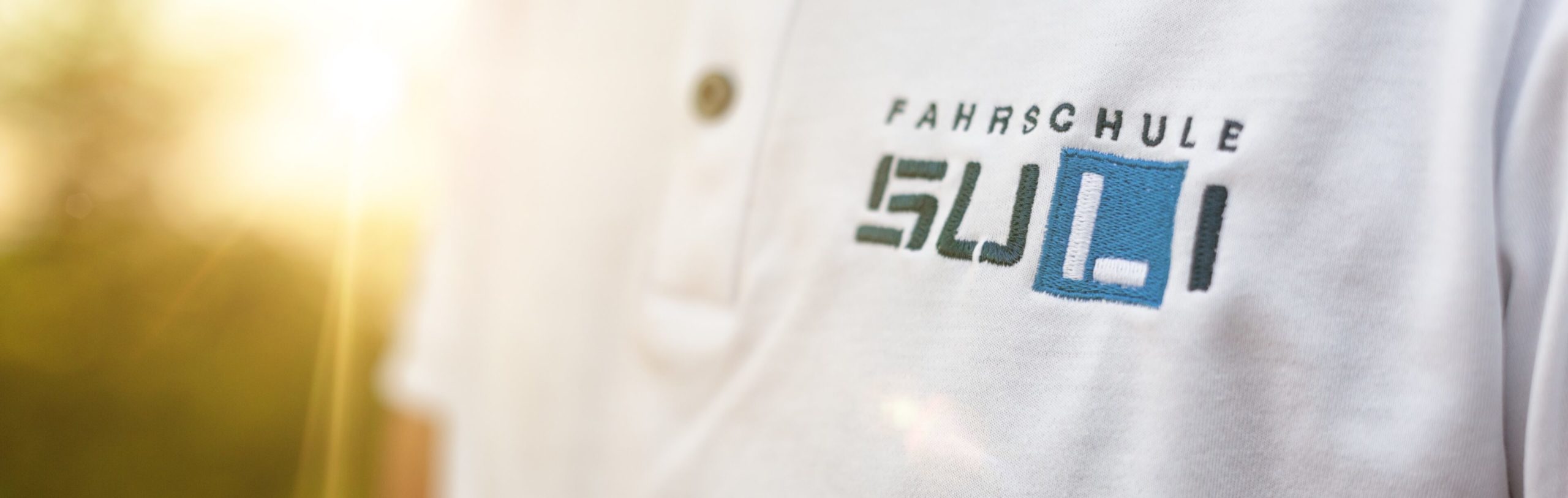 Mitarbeiter der Fahrschule Suli trägt ein Fahrschul-Shirt und ist dabei, auf eine Preis- oder Angebotsseite zu blicken.