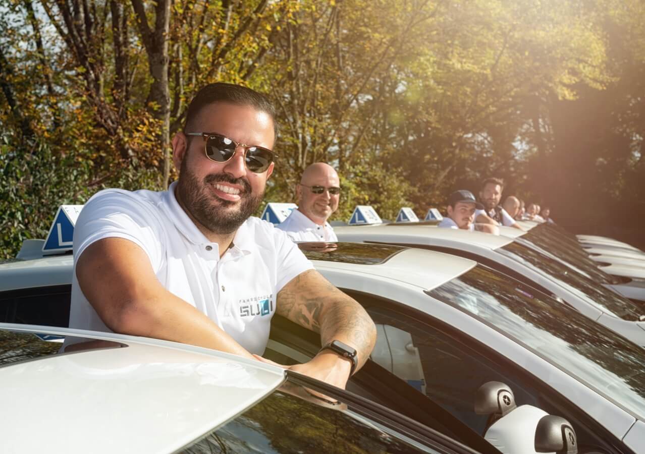 Unsere Fahrlehrer bei ihren Autos, mit Cristo im Vordergrund, einem wertvollen Teammitglied.