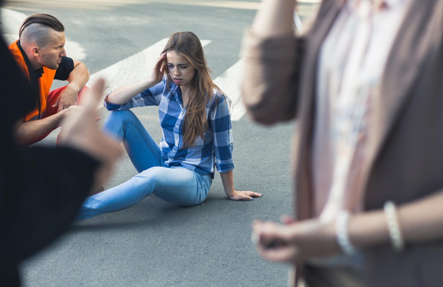Eine sichtlich verwirrte Person sitzt am Strassenrand, während im Hintergrund andere Kursteilnehmende oder ein Ersthelfer zu sehen sind.