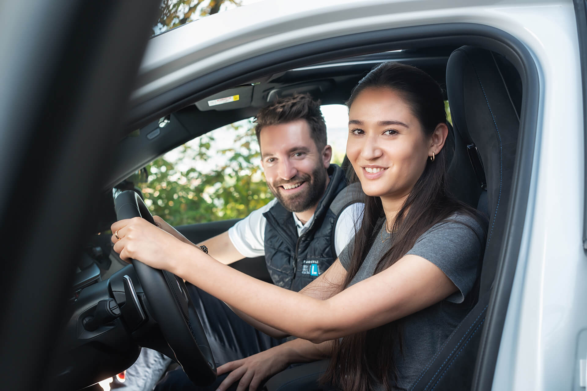 Fahrlehrer und begeisterte Schülerin im Auto – Freude am Fahren erleben