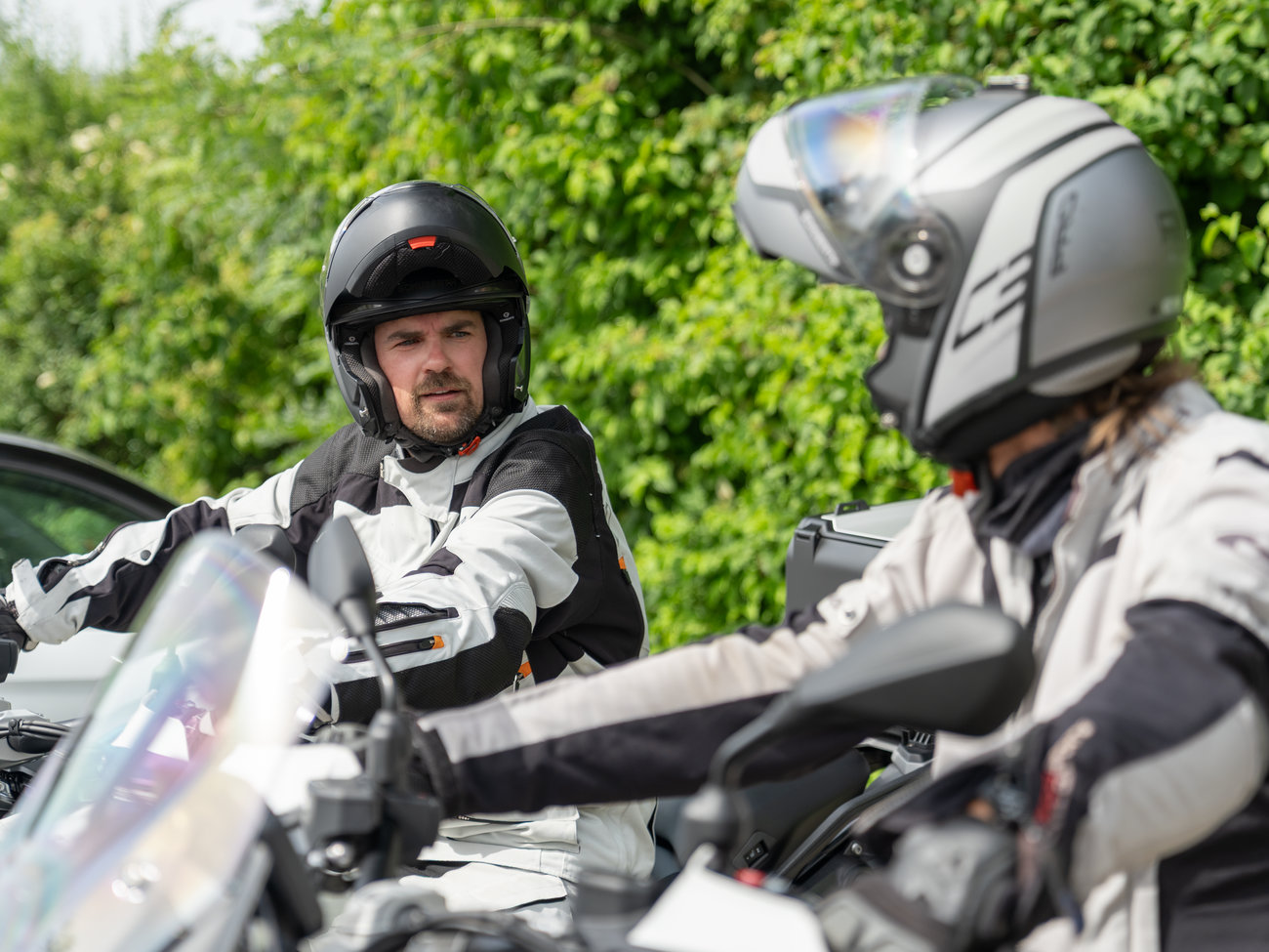 Fahrlehrer erklärt einem Fahrschüler wichtige Inhalte des Motorrad-Grundkurses.